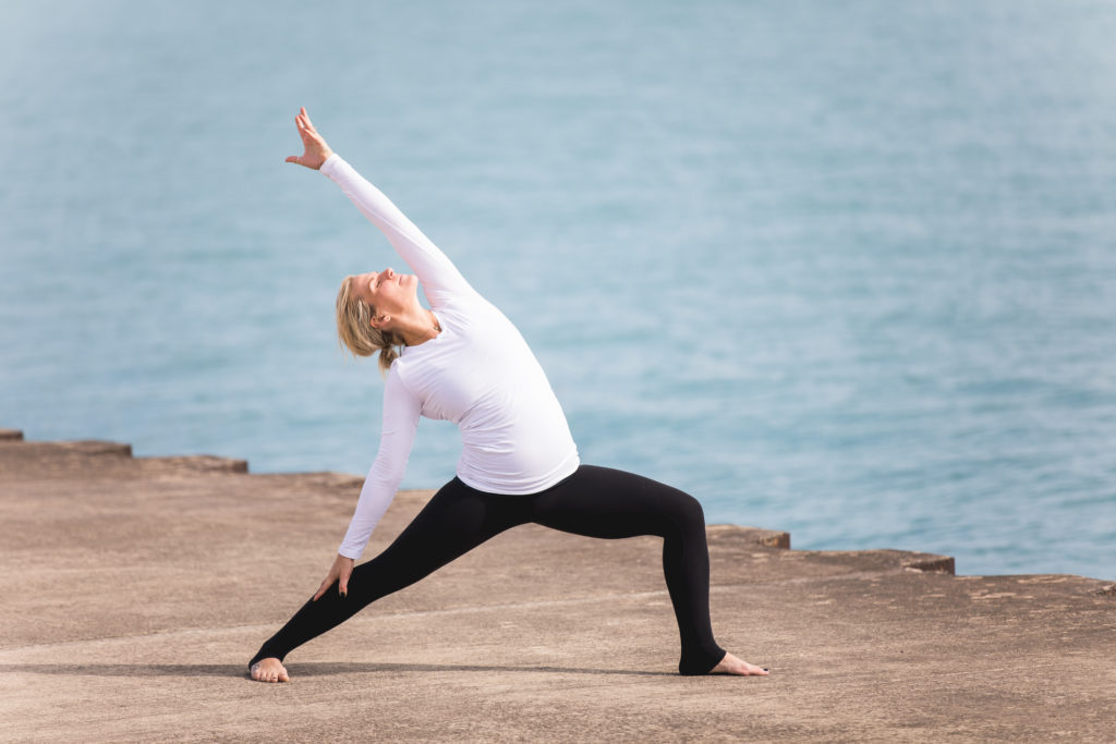 Pregnant Woman with Husband Expecting Baby with Yoga Pose at Beach