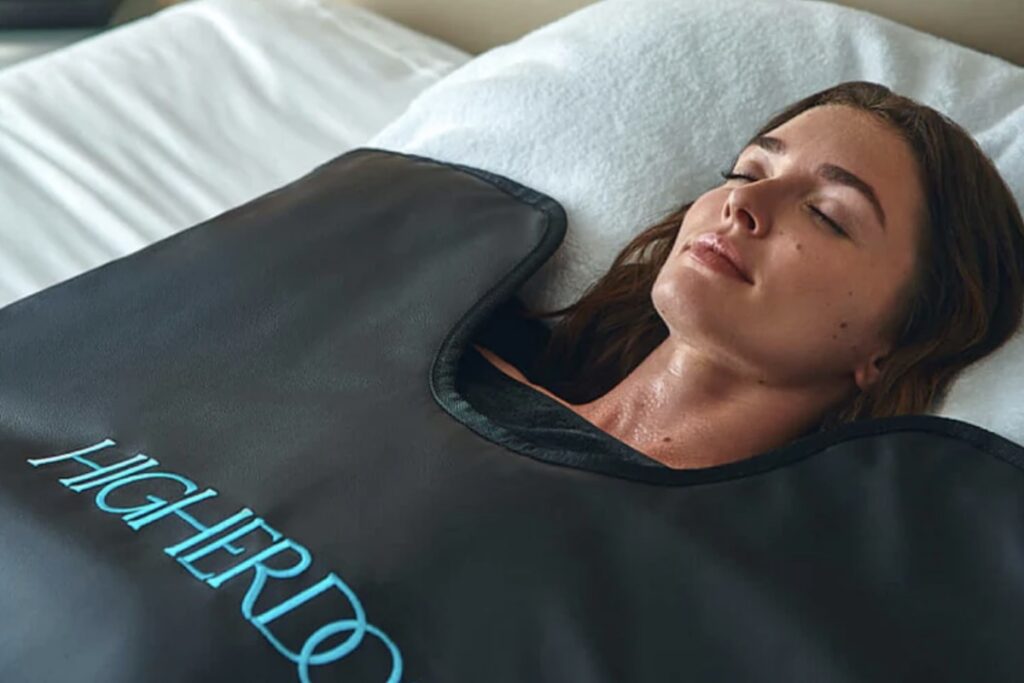 person lying under infrared sauna blanket