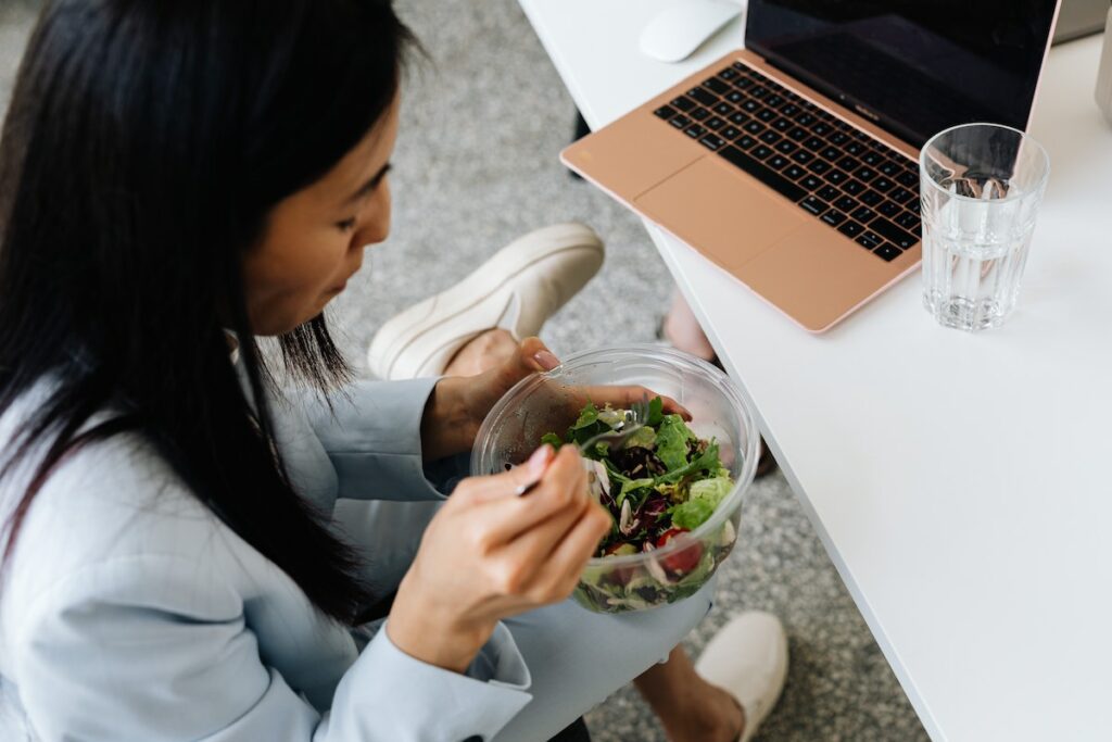 person eating salad at desk