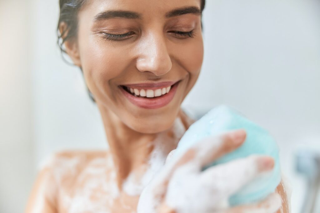 person exfoliating skin in shower