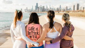 women arm in arm looking down the beach